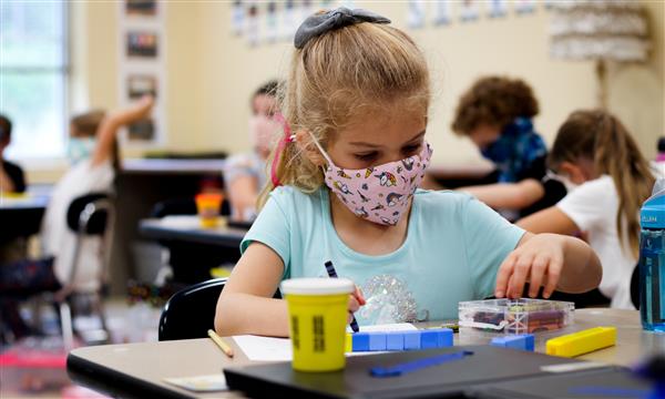 girl working at desk while wearing mask